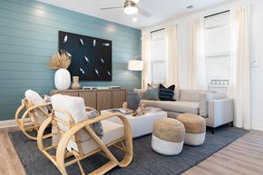 Leland apartment for rent - A living room with a white sofa, a wooden rocking chair, and a large painting on the wall.