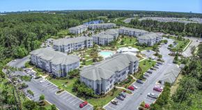 Myrtle Beach apartment for rent - A bird's eye view of a resort with multiple buildings, a swimming pool, and a parking lot.