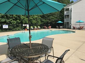 Fayetteville apartment for rent - a swimming pool with a table and chairs under an umbrella with chairs.