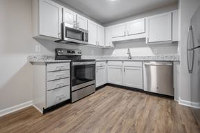 Raleigh apartment for rent - A kitchen with white cabinets and a wooden floor.