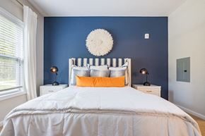 Knightdale apartment for rent - a bedroom with blue walls and a white bed with orange pillows