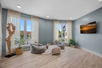 Greensboro apartment for rent - A living room with a large window, a wooden floor, and a painting on the wall.