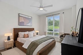 Greensboro apartment for rent - A bedroom with a large bed, a ceiling fan, and a painting on the wall.