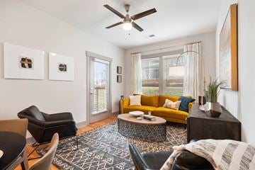 Asheville apartment for rent - A living room with a yellow couch and a ceiling fan.
