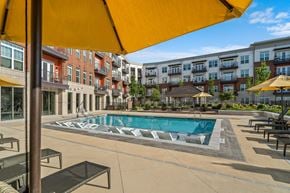 Greensboro apartment for rent - a swimming pool with umbrellas in front of an apartment building