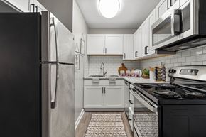 Winston Salem apartment for rent - a kitchen with white cabinets and black appliances and a refrigerator