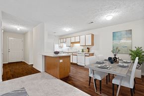 Fayetteville apartment for rent - A white dining room with a table and chairs surrounding and kitchen in the background.