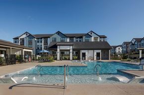 High Point apartment for rent - A large swimming pool in front of a building at Evolve Deep River Apartments in High Point, NC