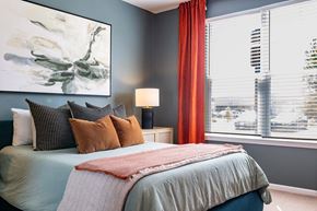 Belville apartment for rent - A bedroom with a large bed and a painting on the wall at Evolve Waterford Apartments in Belville, NC