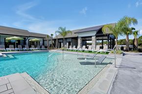 Palm Coast apartment for rent - A large swimming pool with a glass barrier and a building in the background.