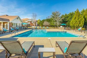Murfreesboro apartment for rent - A pool surrounded by chairs and trees.