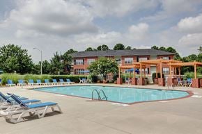 Raleigh apartment for rent - A pool with chairs and a building in the background.