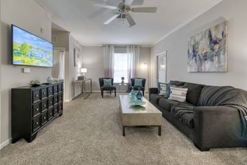 Orange City apartment for rent - A living room with a grey couch, a black cabinet, a coffee table, and a television on the wall.