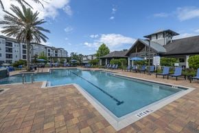 Jacksonville apartment for rent - A large outdoor swimming pool surrounded by lounge chairs and umbrellas.