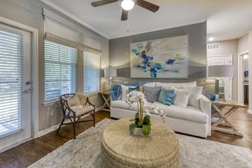 Jacksonville apartment for rent - A living room with a white couch, a table with a vase of flowers, and a painting on the wall.