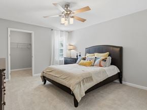 Athens apartment for rent - A bedroom with a bed, a ceiling fan, and a window with curtains.