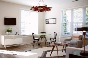 N Charleston apartment for rent - A living room with a white cabinet, a black TV, a wooden table and chairs, and a red chandelier.
