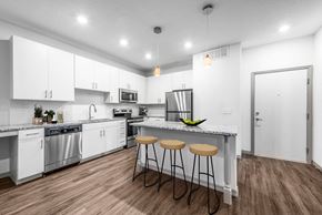 Kissimmee apartment for rent - a kitchen with white cabinets and a counter top with three stools