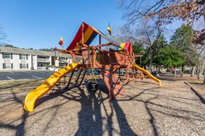 Greensboro apartment for rent - A playground with a yellow slide and a red and yellow structure at Madison Woods apartments in Greensboro, NC.