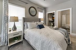 Jacksonville apartment for rent - A bedroom with a large bed, a nightstand with a lamp, and a mirror on the wall.