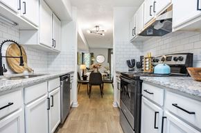 Greensboro apartment for rent - a kitchen with white cabinets and black appliances and a dining room with a table