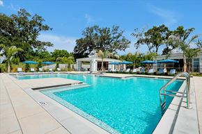 Wildwood apartment for rent - A large swimming pool with a metal railing and a building in the background.
