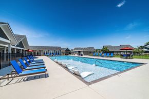 Madison apartment for rent - A swimming pool with blue lounge chairs and a red roofed building in the background.