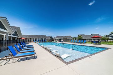 Madison apartment for rent - A swimming pool with blue lounge chairs and a red roofed building in the background.