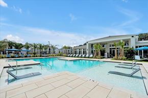 Wildwood apartment for rent - A large outdoor swimming pool with loungers and a building in the background.
