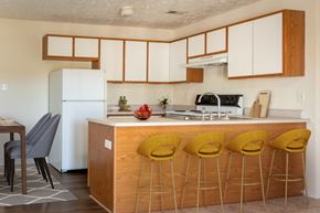 Hope Mills apartment for rent - a kitchen with white cabinets and a counter with yellow chairs