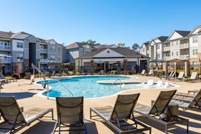 Fayetteville apartment for rent - A pool surrounded by lounge chairs in front of apartment buildings.