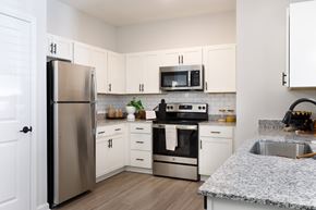 Fayetteville apartment for rent - A kitchen with a refrigerator, microwave, oven, and sink.