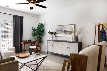 Fayetteville apartment for rent - A living room with a ceiling fan, a chair, a table, a cabinet, and a painting on the wall.
