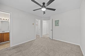 Greenville apartment for rent - A bedroom with a ceiling fan and carpeted flooring plus view into the bathroom.