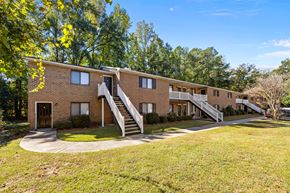 Greenville apartment for rent - Exterior of complex brick building with three sets of stairs going down into a green grass lawn.