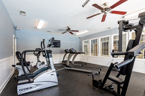 Raleigh apartment for rent - A home gym with a treadmill, elliptical trainer, and a fan.