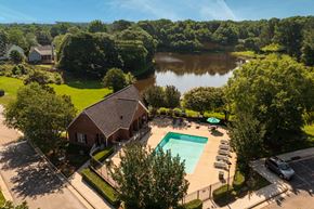 Raleigh apartment for rent - an aerial view of a house with a swimming pool and a lake in the background