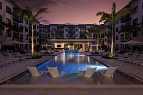 Fort Myers apartment for rent - A large swimming pool surrounded by lounge chairs and palm trees.