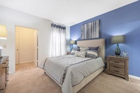 Greensboro apartment for rent - furnished bedroom with blue accent wall and a bed with white comforter
