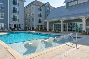 Wilmington apartment for rent - A pool with white chairs and a building in the background.
