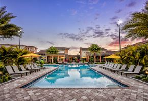 Kissimmee apartment for rent - a swimming pool with lounge chairs around it at sunset