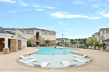Holly Springs apartment for rent - A swimming pool surrounded by white lounge chairs in front of apartment buildings.
