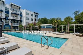 Wilmington apartment for rent - A swimming pool surrounded by lounge chairs and apartment buildings.