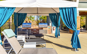 Wilmington apartment for rent - A white canopy with blue curtains is set up over a patio area with lounge chairs and tables.