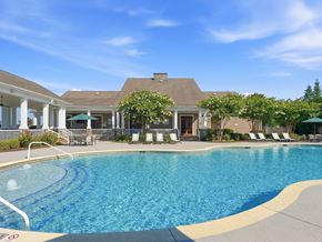 Warner Robins apartment for rent - A large swimming pool in front of a house with a patio and lounge chairs.