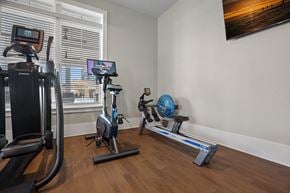 Mooresville apartment for rent - A home gym with a treadmill, exercise bike, rowing machine, and weights.