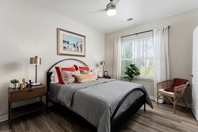 New Bern apartment for rent - A bedroom with a bed, chair, and a painting on the wall.