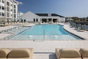 Fort Myers apartment for rent - A large swimming pool surrounded by lounge chairs and umbrellas.