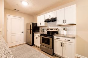 Spring Lake apartment for rent - A kitchen with white cabinets and a black refrigerator.
