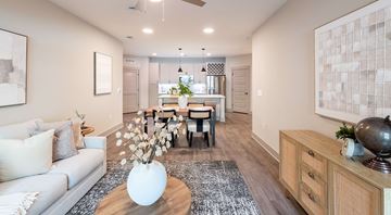 Cary apartment for rent - A living room with a grey couch, a coffee table, and a dining table with chairs.